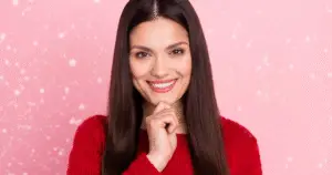 A woman wearing a red sweater smiling into the camera with joy.
