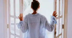 Young lady, back to the camera, facing the open french doors as part of her Morning Routine