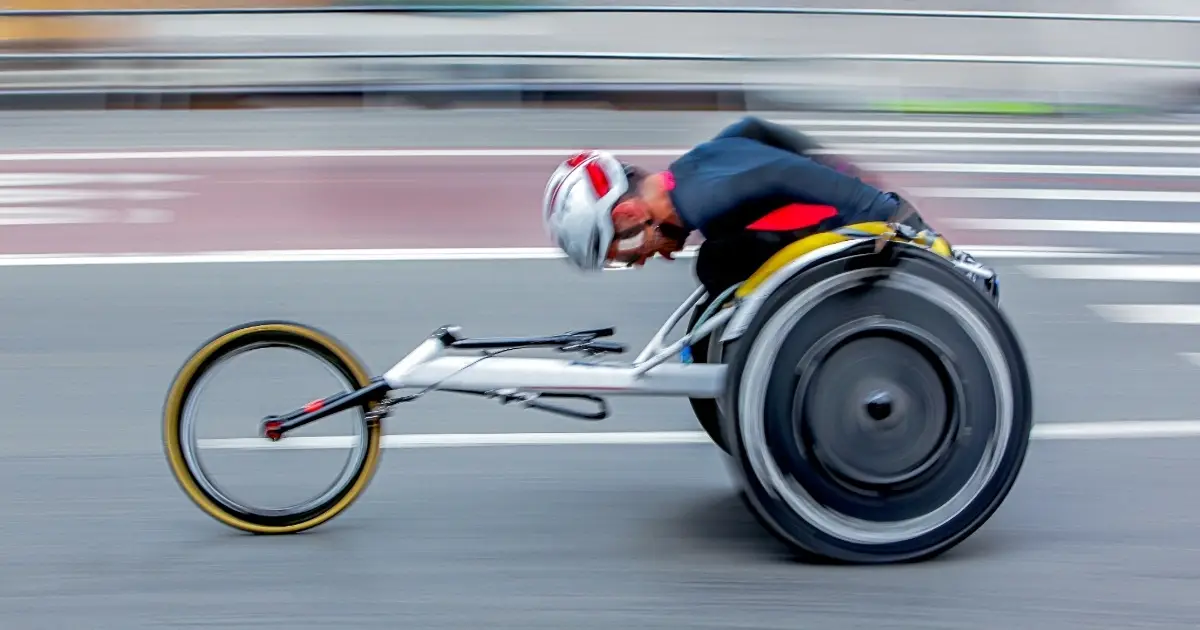 An amputee cyclist leaning forward to cycle to the finish line.