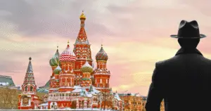 A shadow of a man wearing a hat and overcoat standing with back turned to camera, facing the fabled St. Petersburg turrets in wintertime in the early morning.