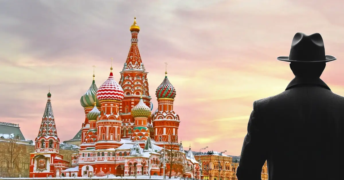 A shadow of a man wearing a hat and overcoat standing with back turned to camera, facing the fabled St. Petersburg turrets in wintertime in the early morning.