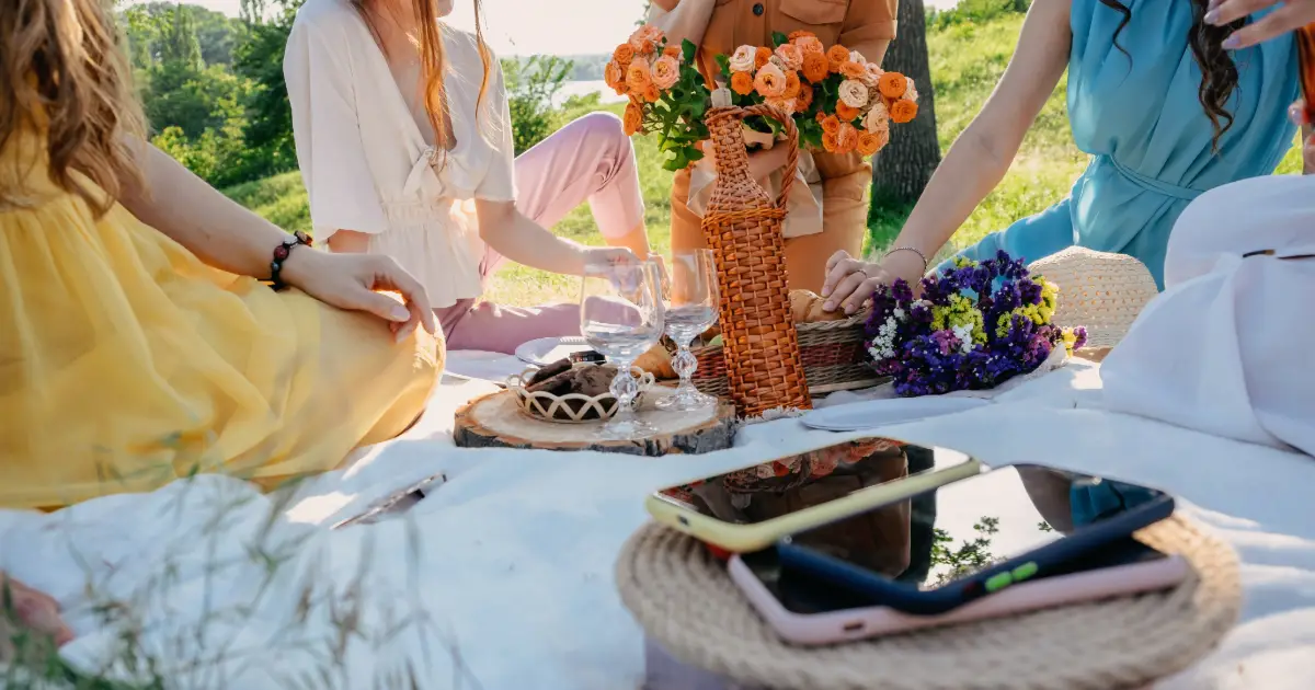 young ladies, on a summer picnic, all their phones are placed to the side